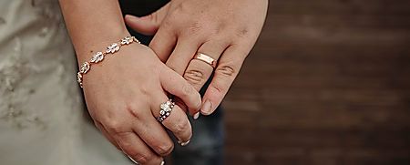 Close-up of a couple holding hands, both wearing rings
